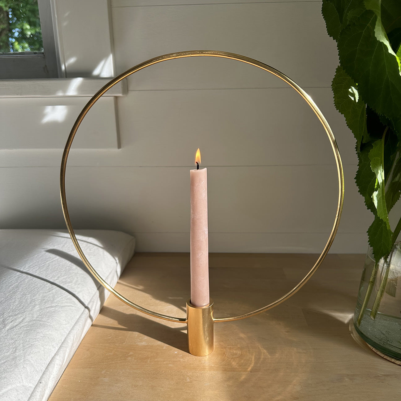 Photo of M+A NYC Halo Taper Holder gleaming in the sun with a lit candle