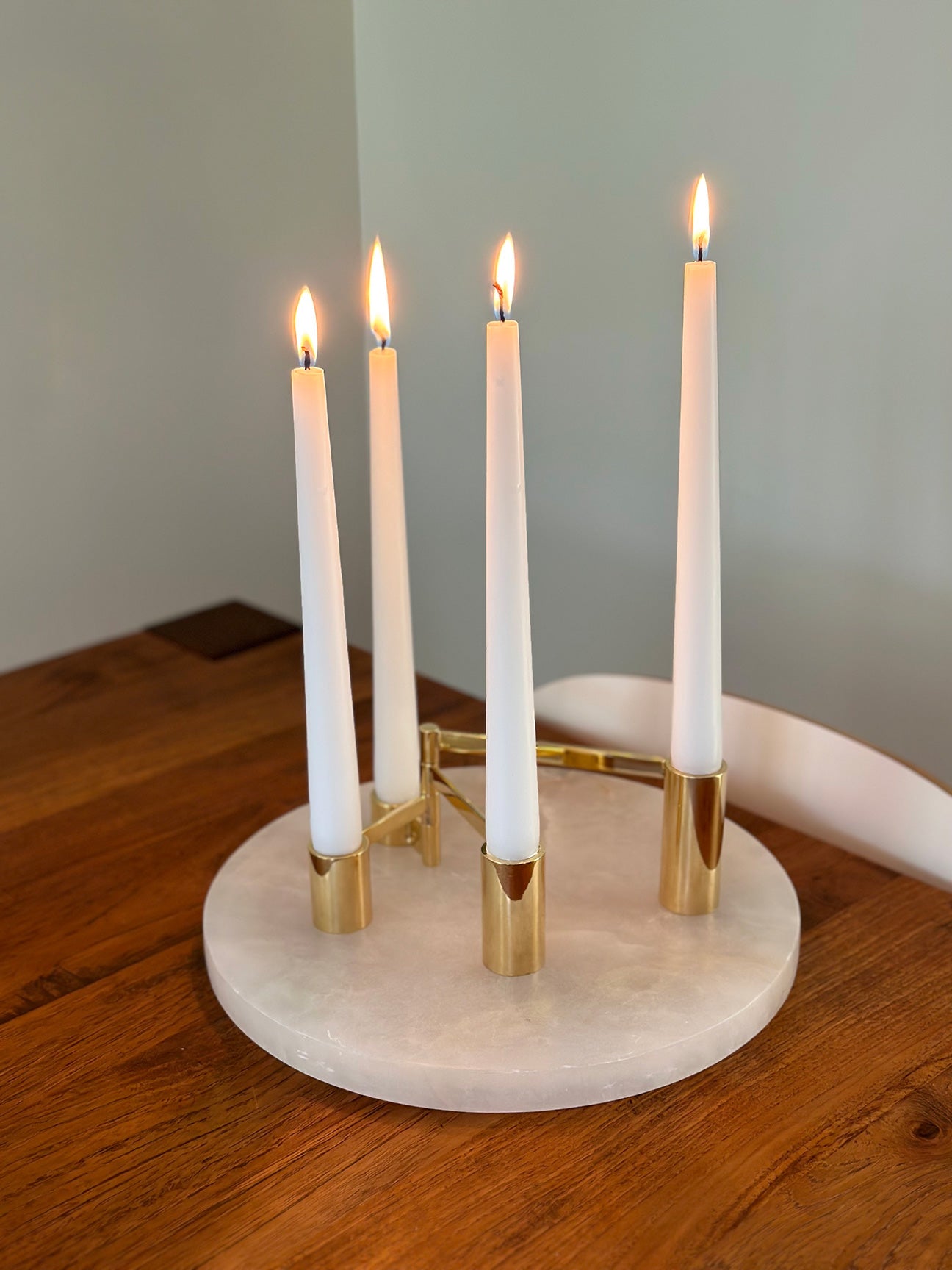 IMAGE OF M+A NYC SOLID BRASS SWING ARM MODULAR CANDELABRA WITH LIT WHITE CANDLES ATOP THEIR ALABASTER ROUND TRAY