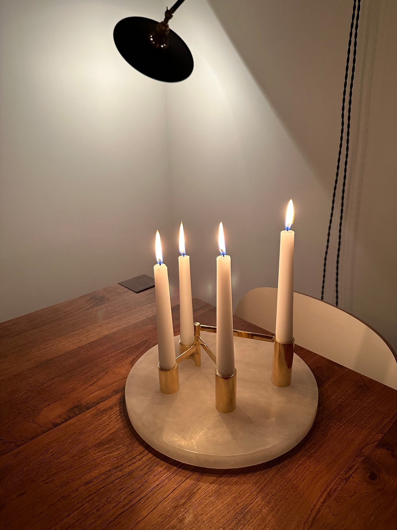 IMAGE OF M+A NYC SOLID BRASS SWING ARM MODULAR CANDELABRA WITH LIT WHITE CANDLES ATOP THEIR ALABASTER ROUND TRAY