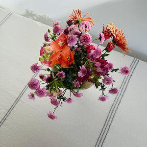 Photo of M+A handloomed cotton textile being used as a tablecloth with a colorful flower arrangement sitting on top of it.