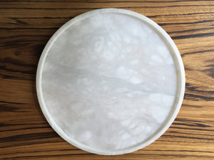 M+A NYC Alabaster Round Tray sitting on a zebrawood tabletop.