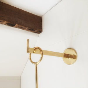 Closeup of M+A NYC Solid Brass Wall Hook mounted on a wall. 