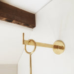 M+A NYC Wall Hook in Polished Brass, 6" Long, mounted on a wall.