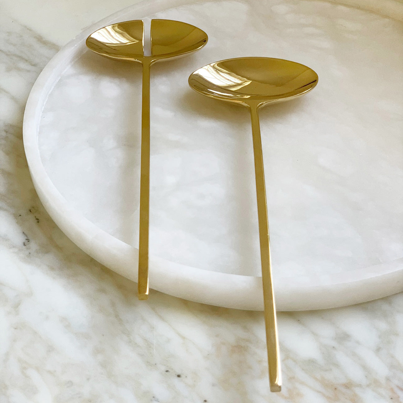 Image of M+A NYC Solid Brass Servers resting on an alabaster tray that is sitting on a marble table.