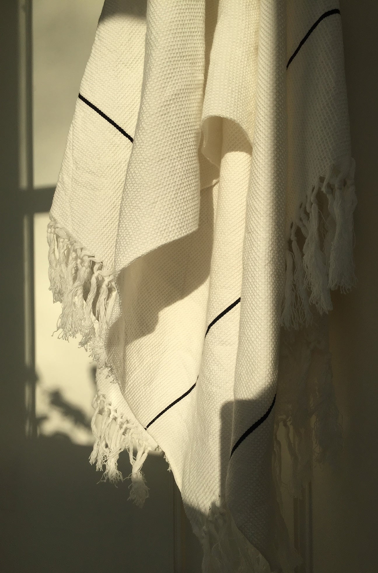 Close up of M+A NYC Honeycomb Bath Sheets draped on a hook at magic hour.