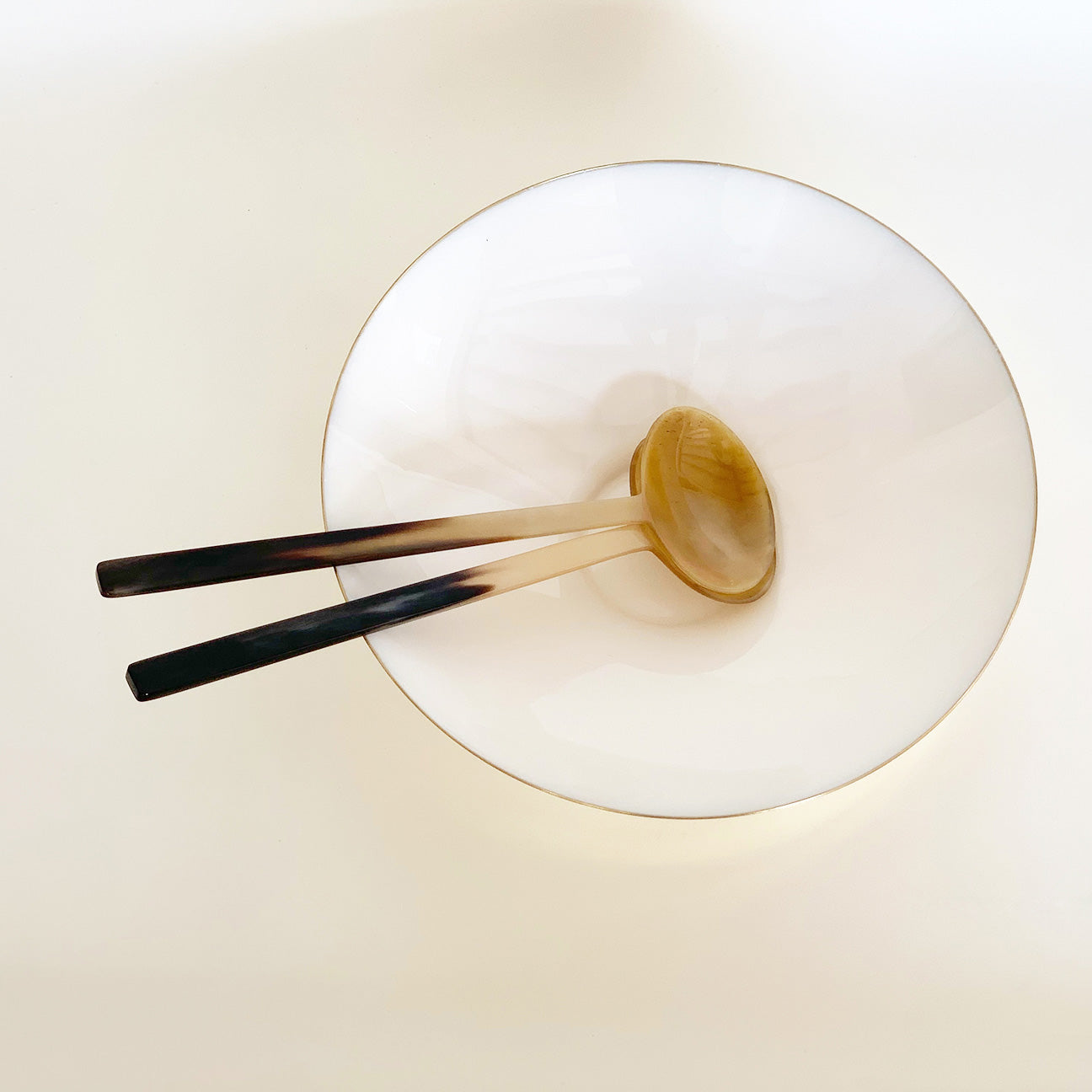 Image of a pair of M+A NYC Amber Horn Servers in a Kora Enamel Bowl