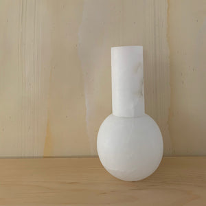 M+A Lolita Vase in Alabaster sitting on a wooden mantel against wallpaper by Fromental Design
