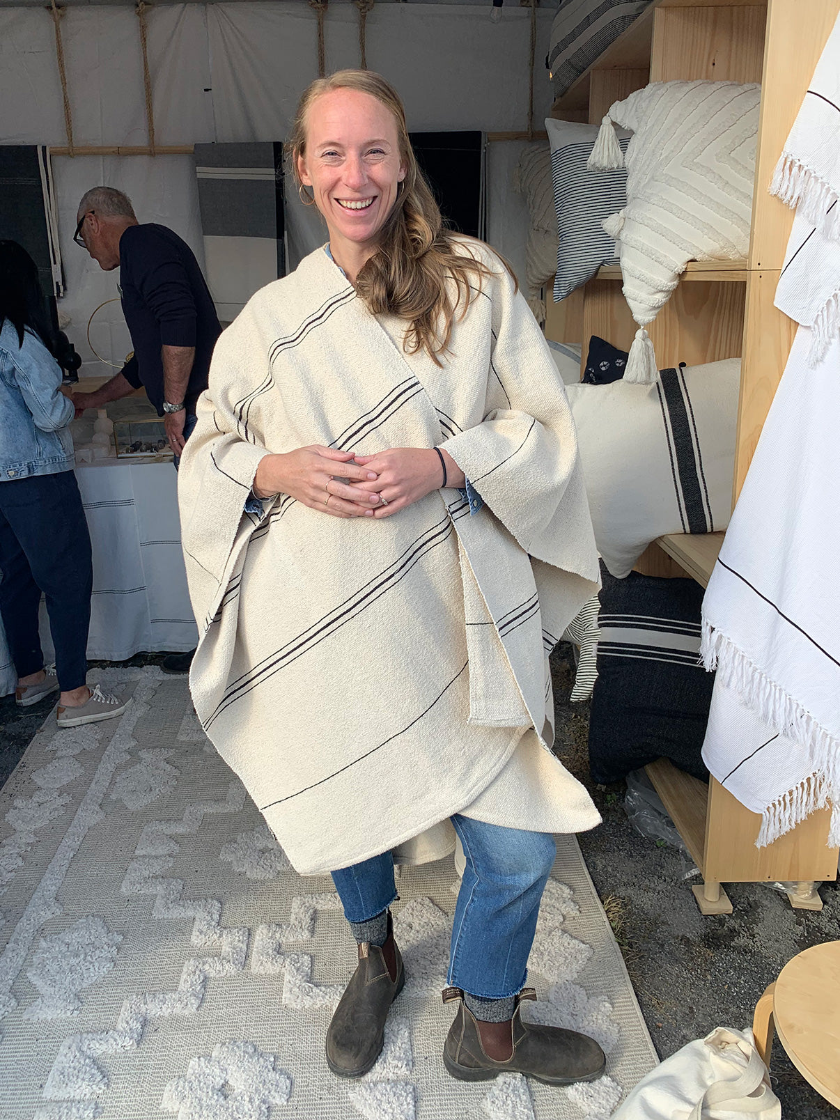 Photo of happy shopper at Field and Supply trying on M+A NYC Hand Loomed Offset Stripe Cape