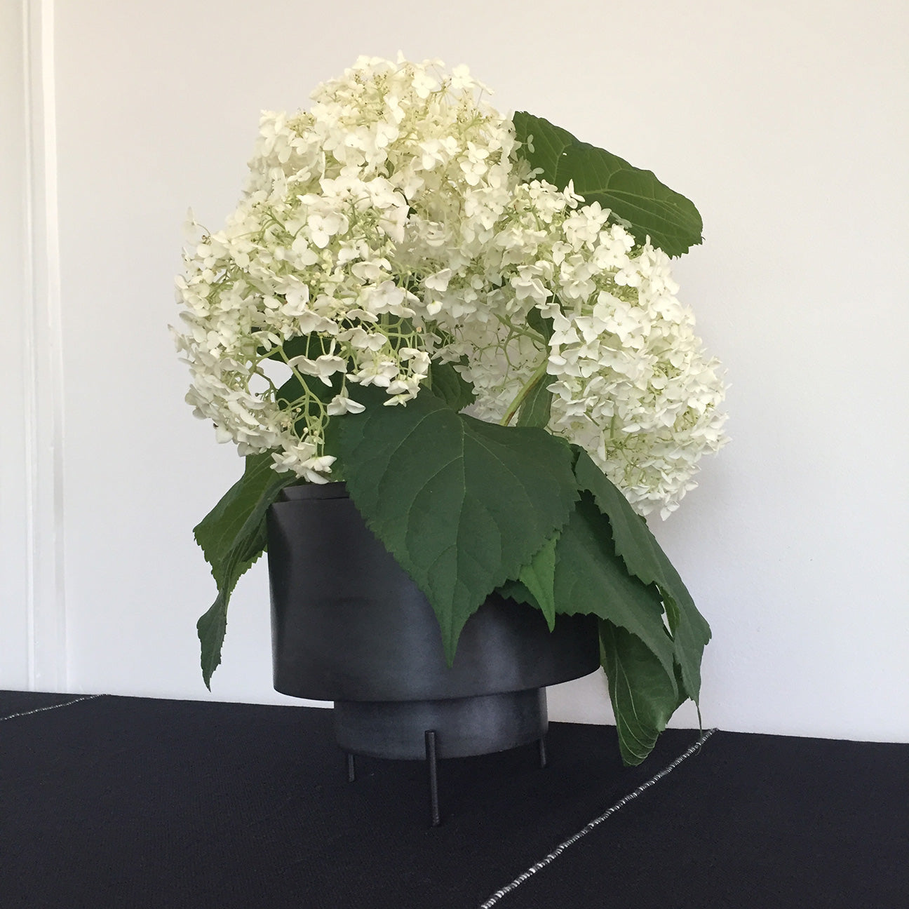Image of M+A NYC Planter/Vase Set in Soapstone being used as a vase for cream colored hydrangeas.