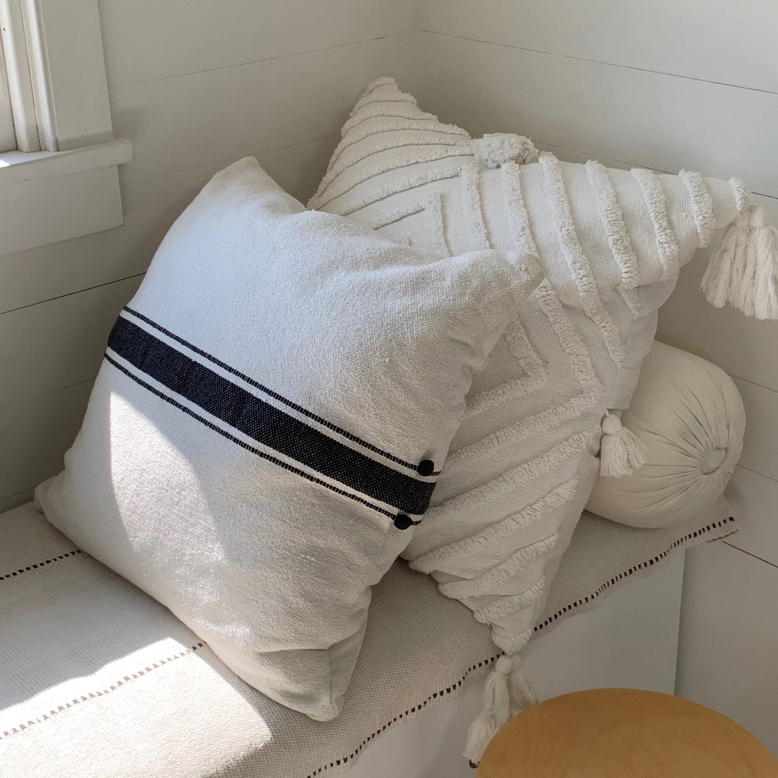 Image of M+A NYC Ribbon Stripe Hand Loomed 24" Pillow reclining on a daybed, and paired with the Stella 26" Pillow in Kora.