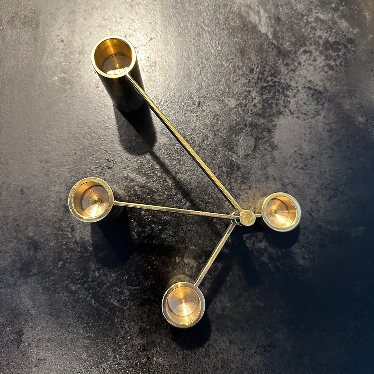 Image of Solid Brass Modular Swing Arm Candelabra sitting on a black cast iron surface.